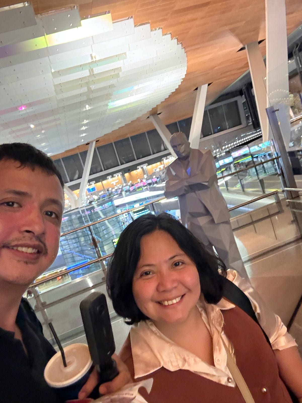 Paolo and Rosed with the low-poly statue overlooking the concourse at Hamad International Airport, Doha