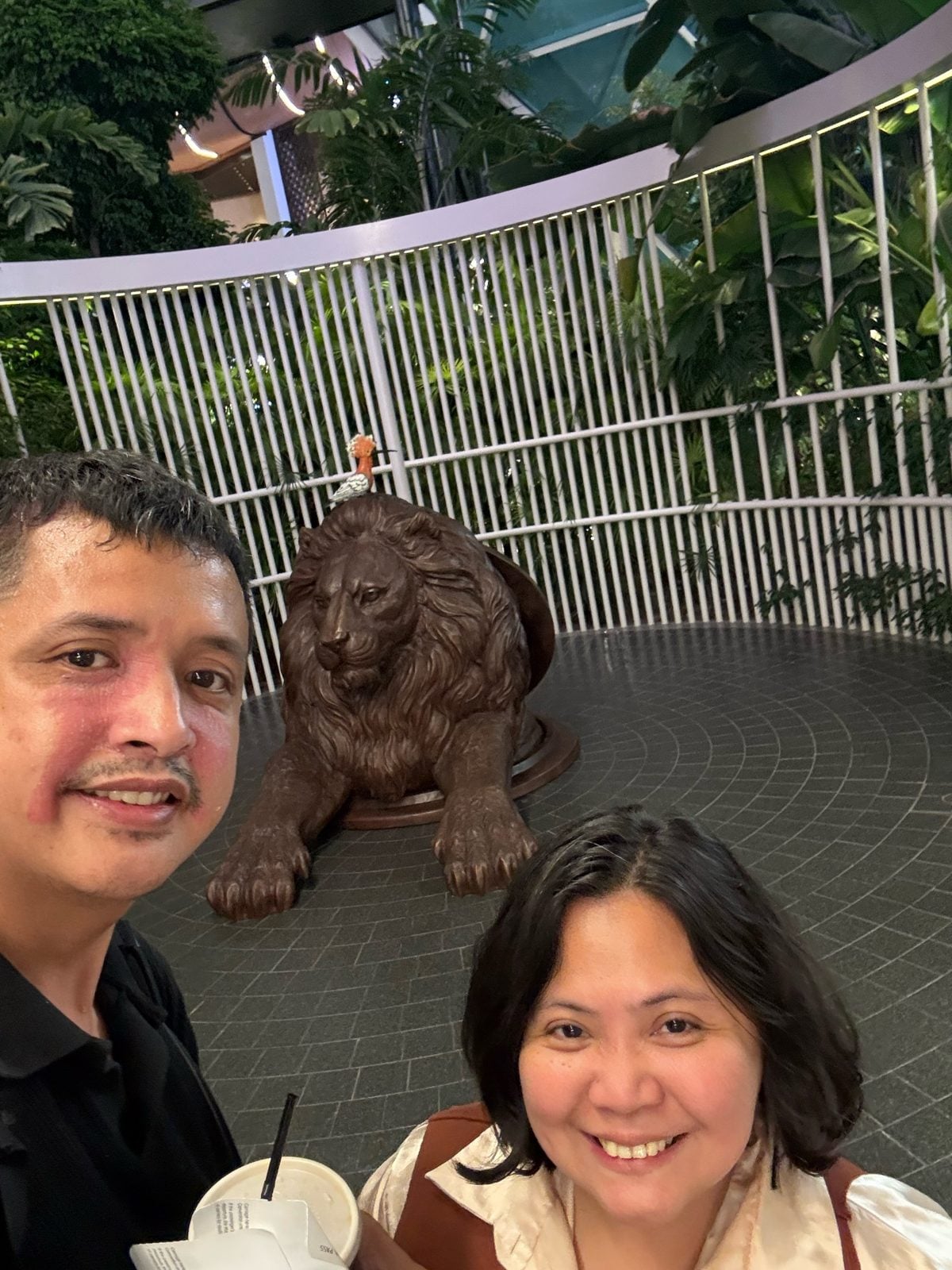 Paolo and Rosed by the bronze lion sculpture in The Orchard at Hamad International Airport, Doha