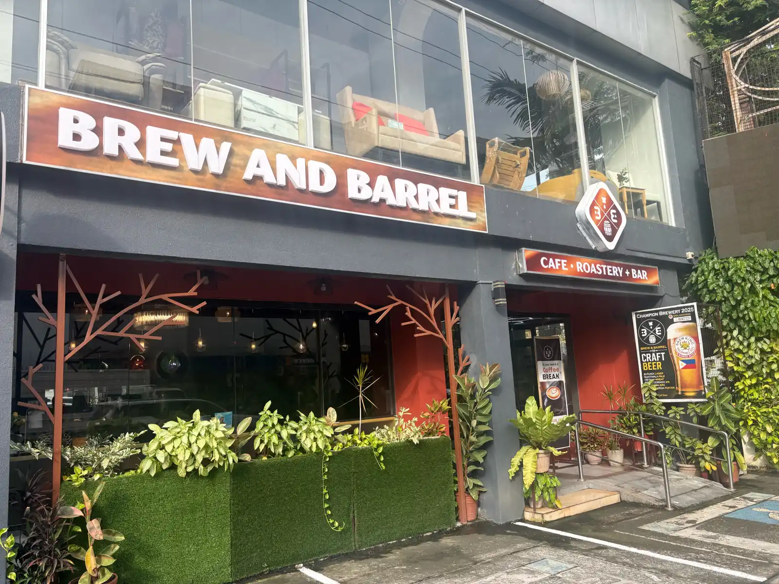 Front of Brew and Barrel Cafe, Roastery and Bar in New Manila, with its red sign and plant boxes