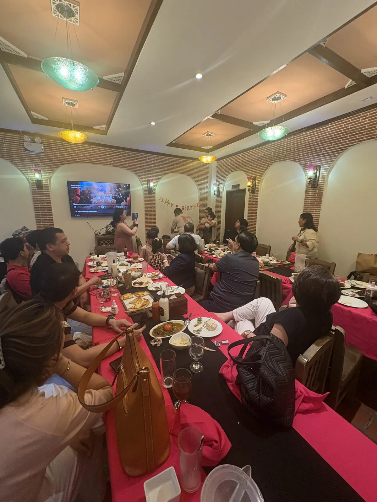 Family seated at a long pink-draped table in a brick-walled function room at Mr Kebab, West Ave, during a birthday celebration