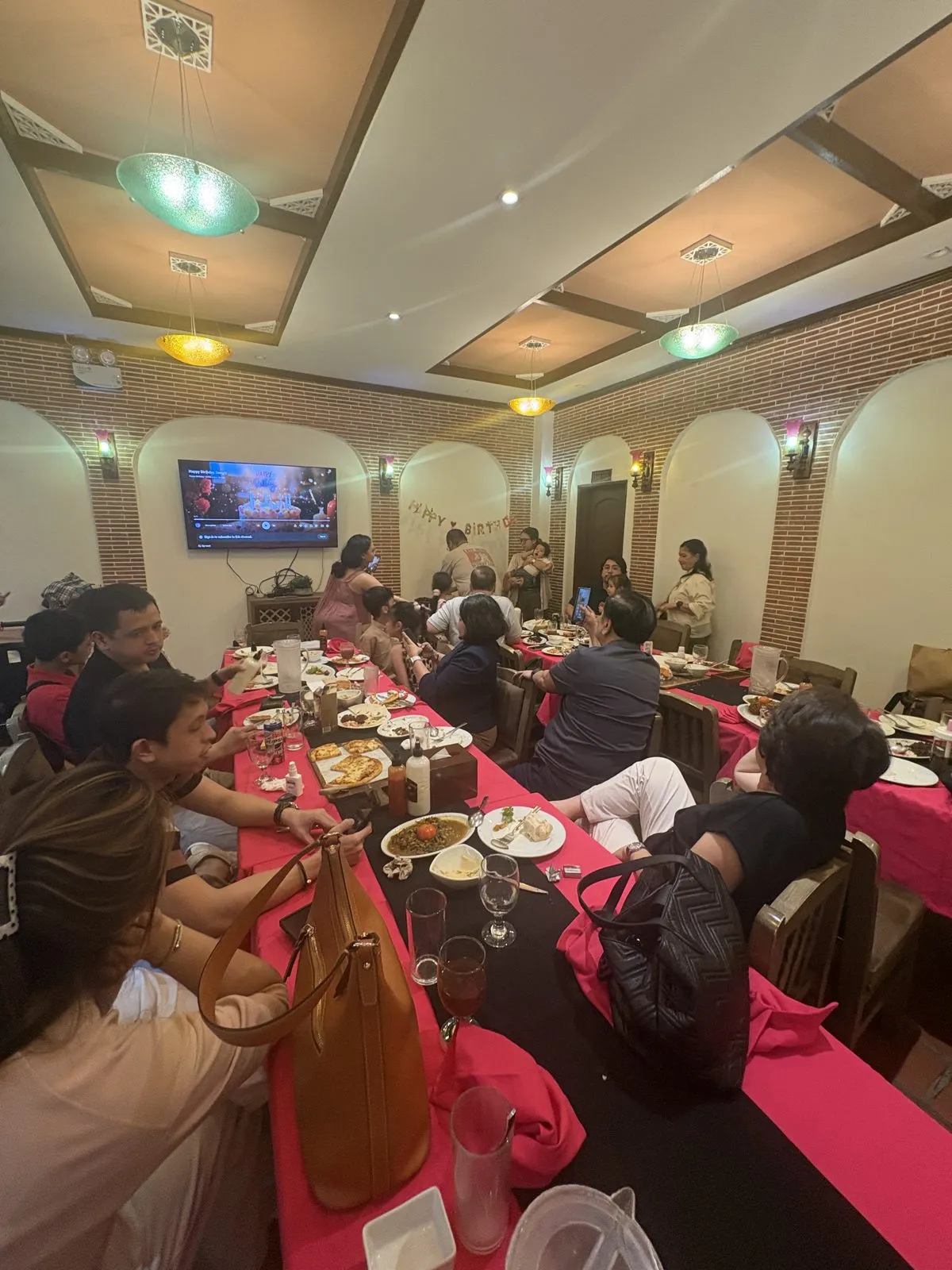 Relatives gathered around the dinner table at Mr Kebab's function room for Carla's birthday, with a Happy Birthday banner on the far wall