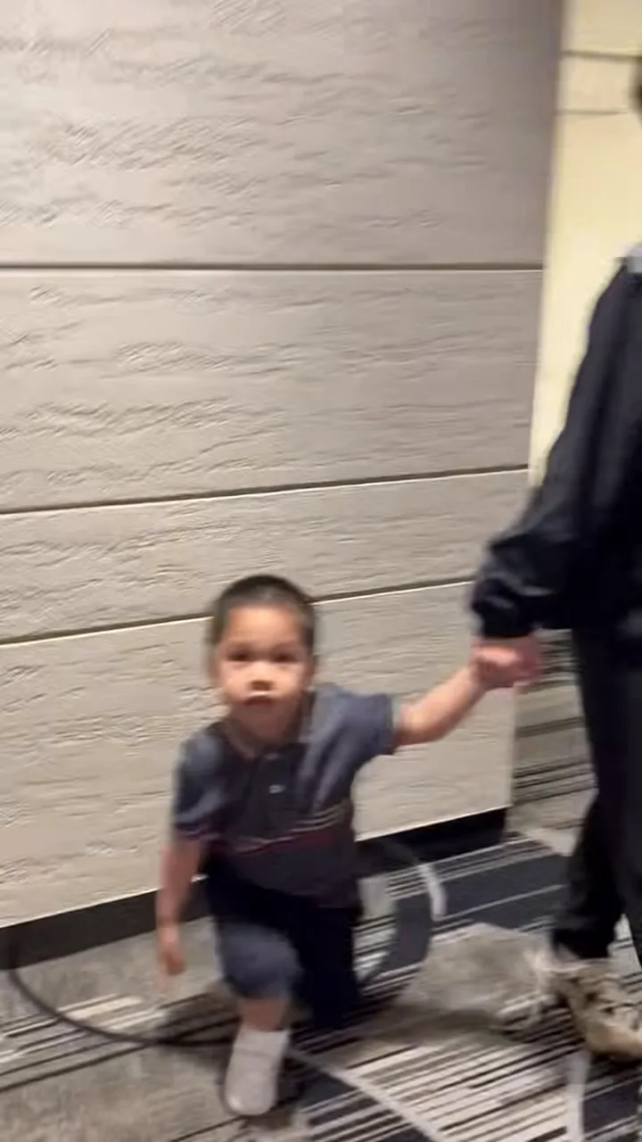 Young boy holding an adult's hand while walking through the arrival hall at Singapore Changi Airport