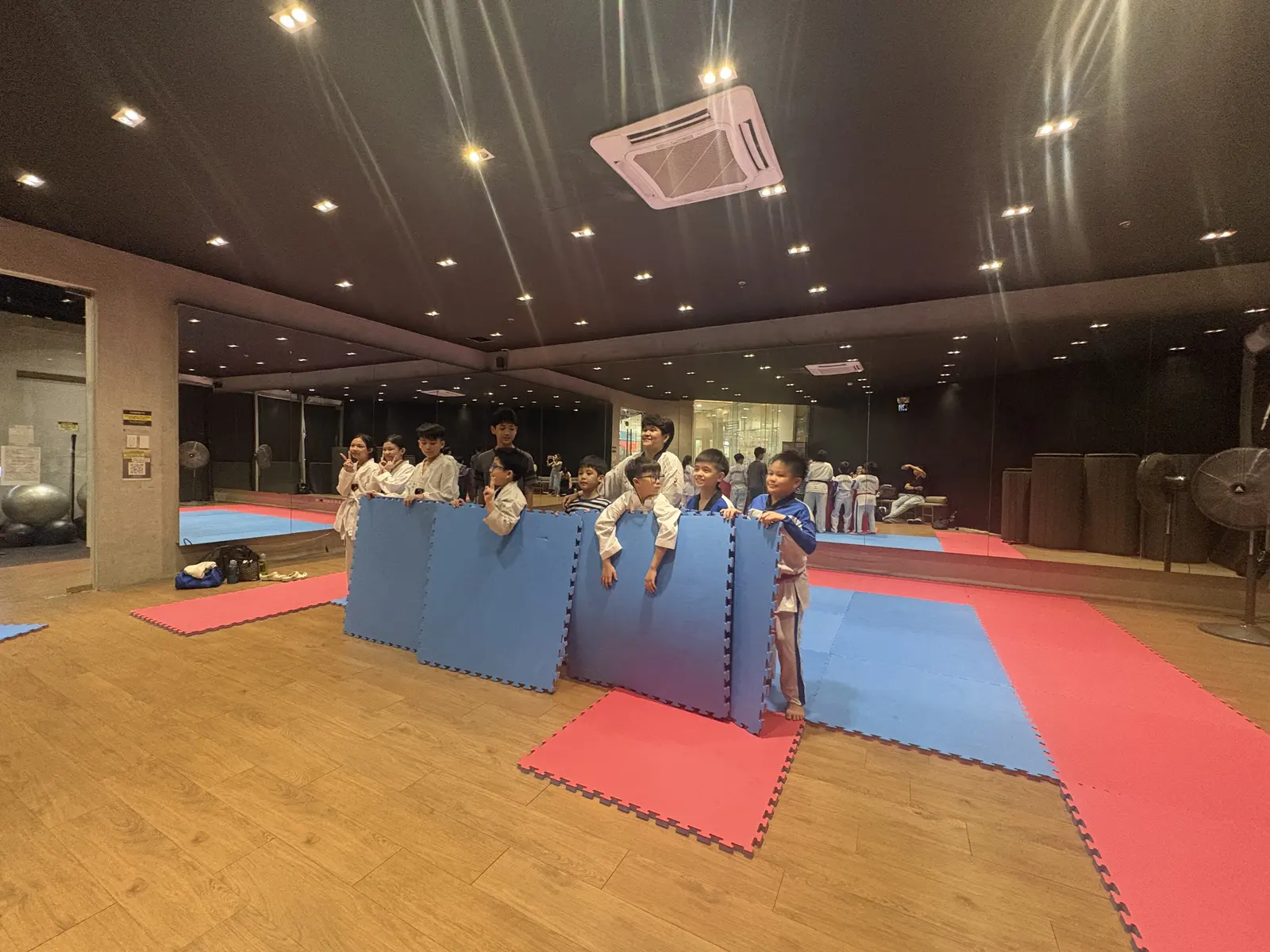 The taekwondo class holding up blue mats for a group photo.