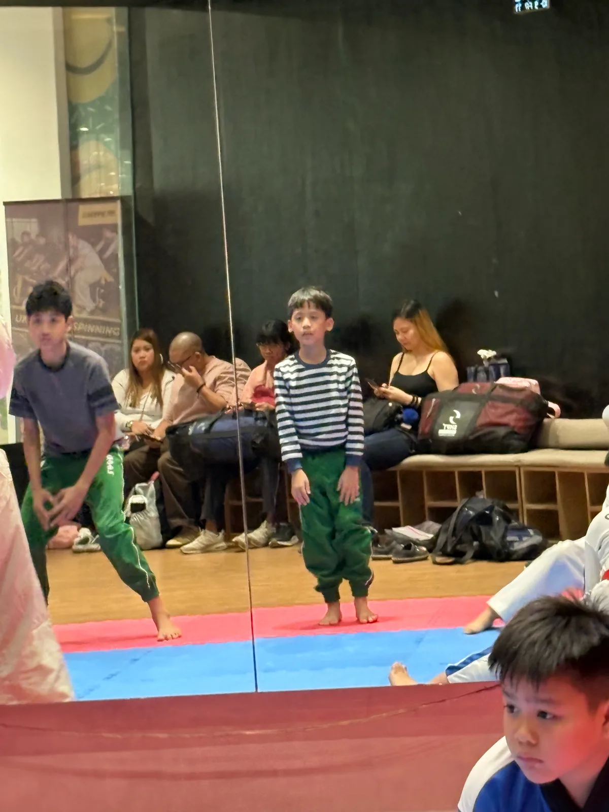 Sky and Ethan in the mirror, waiting for their turn in taekwondo class