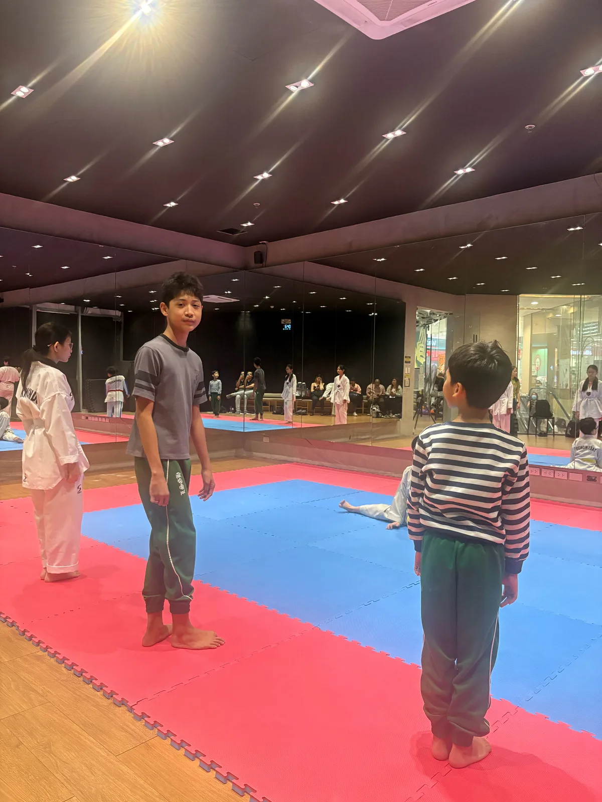 Ethan and Sky standing on the mats, ready for their first taekwondo lesson