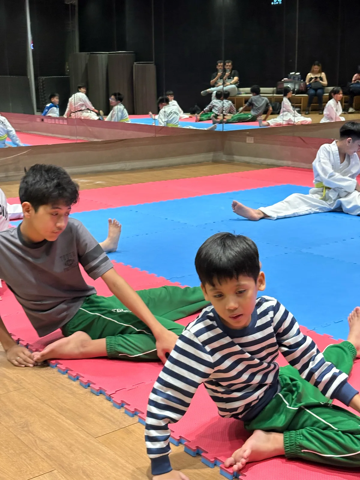 Ethan and Sky stretching on the mats at their first taekwondo class