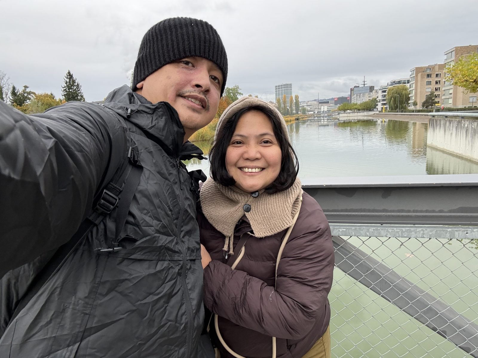 Paolo and Rosed smiling on a bridge over calm water in Zurich