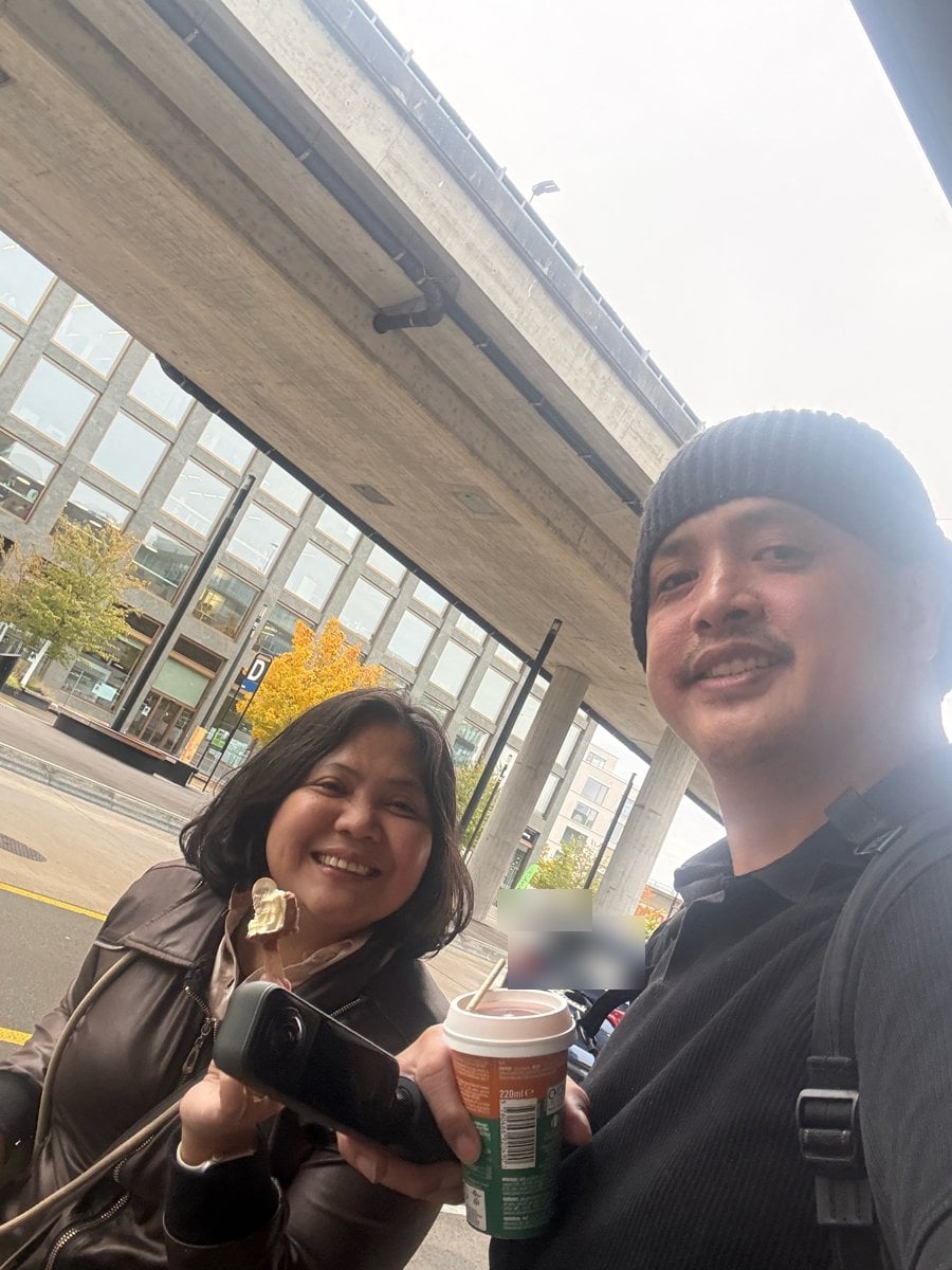 Paolo and Rosed smiling with ice cream and coffee under the overpass, yellow autumn trees behind them, outside Glatt