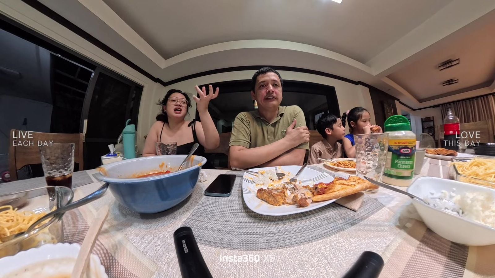 Family eating together at Lola's birthday dinner, with KFC, pizza and spaghetti on the table