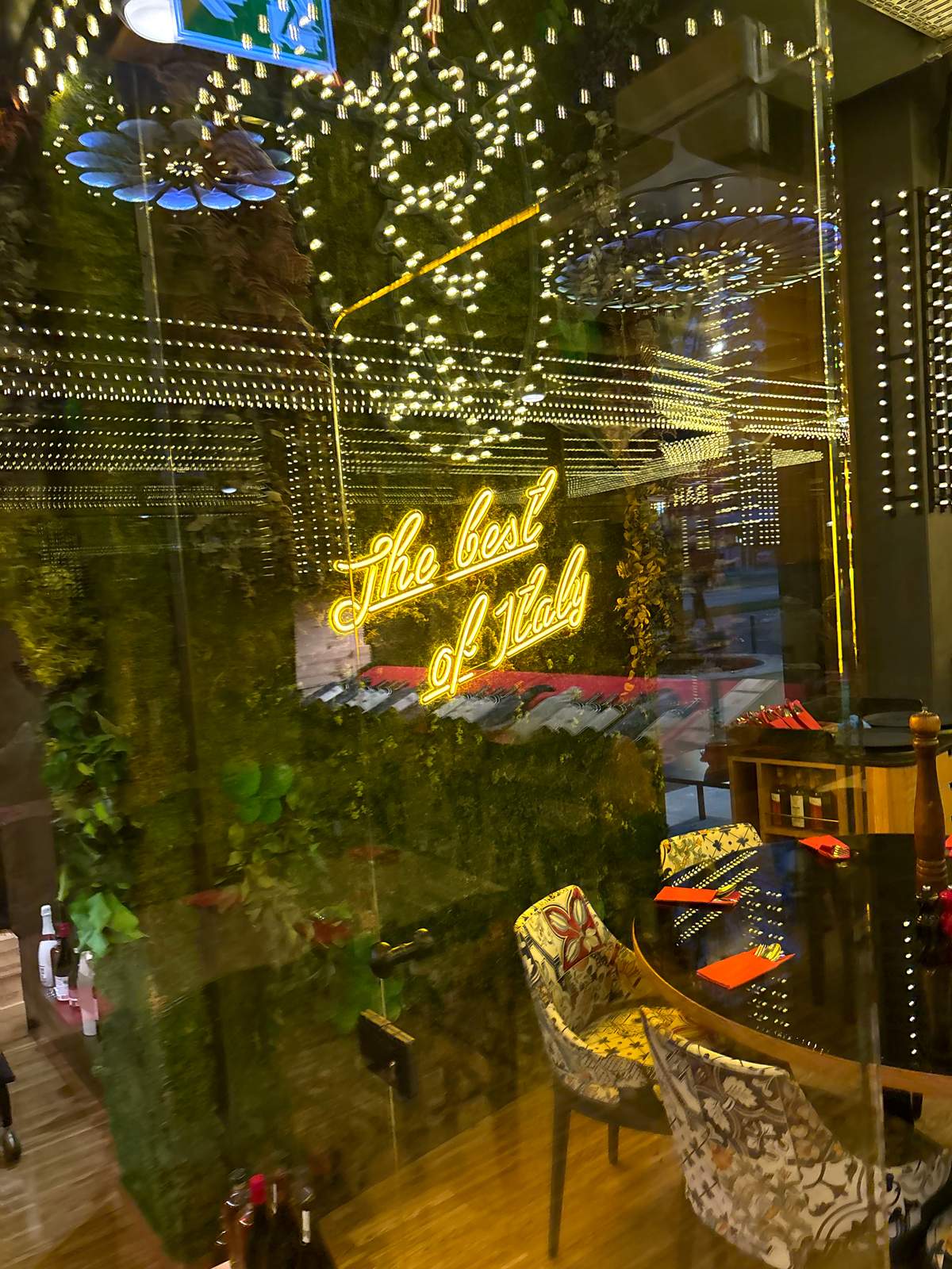 "The best of Italy" neon sign on a green plant wall inside Luigia Opfikon