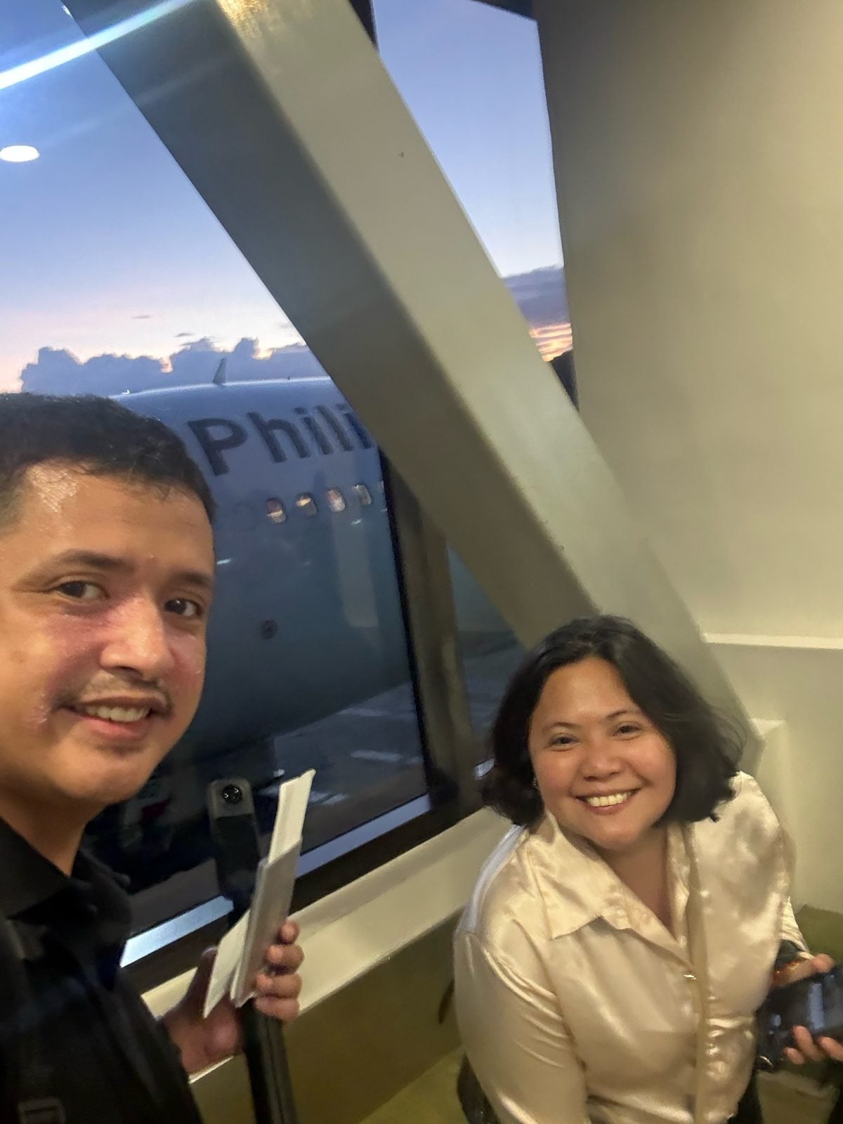 Paolo and Rosed at the gate with a Philippine Airlines plane at sunset at NAIA Terminal 1, Manila