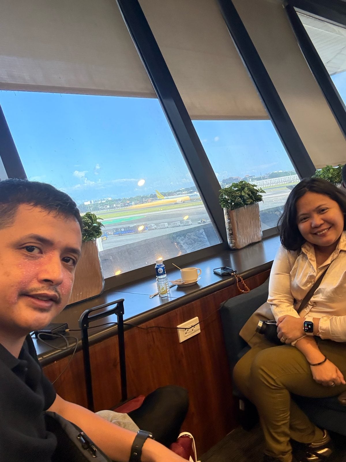 Paolo and Rosed by the runway-view windows of the PAGSS lounge at NAIA Terminal 1, Manila