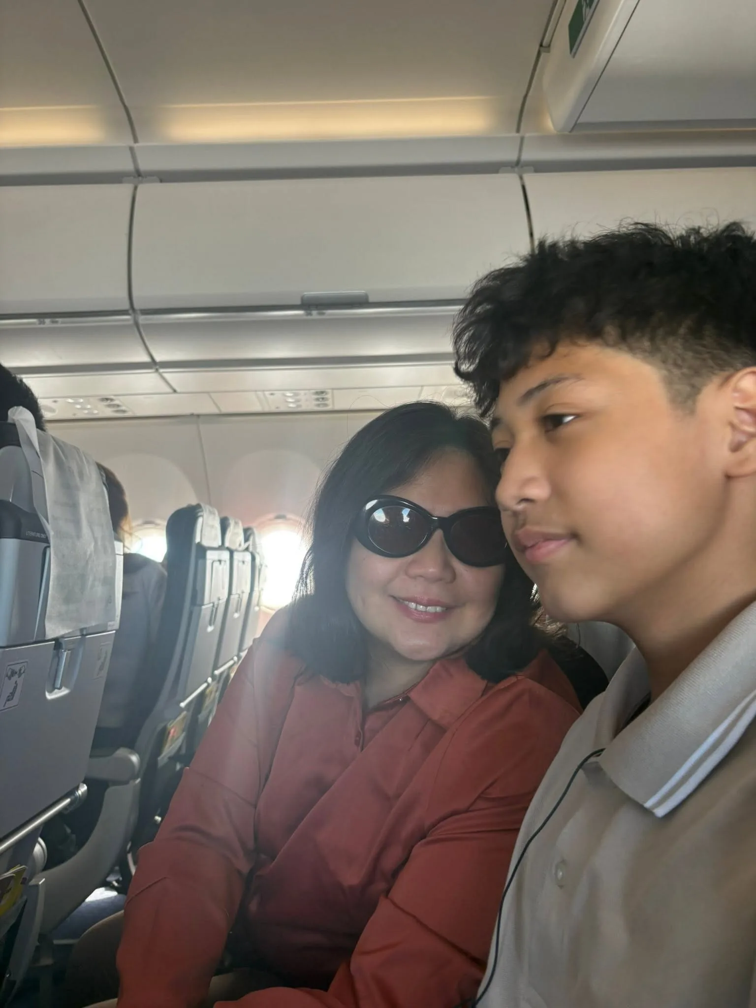 Lola in sunglasses with a grandson on the plane to Singapore