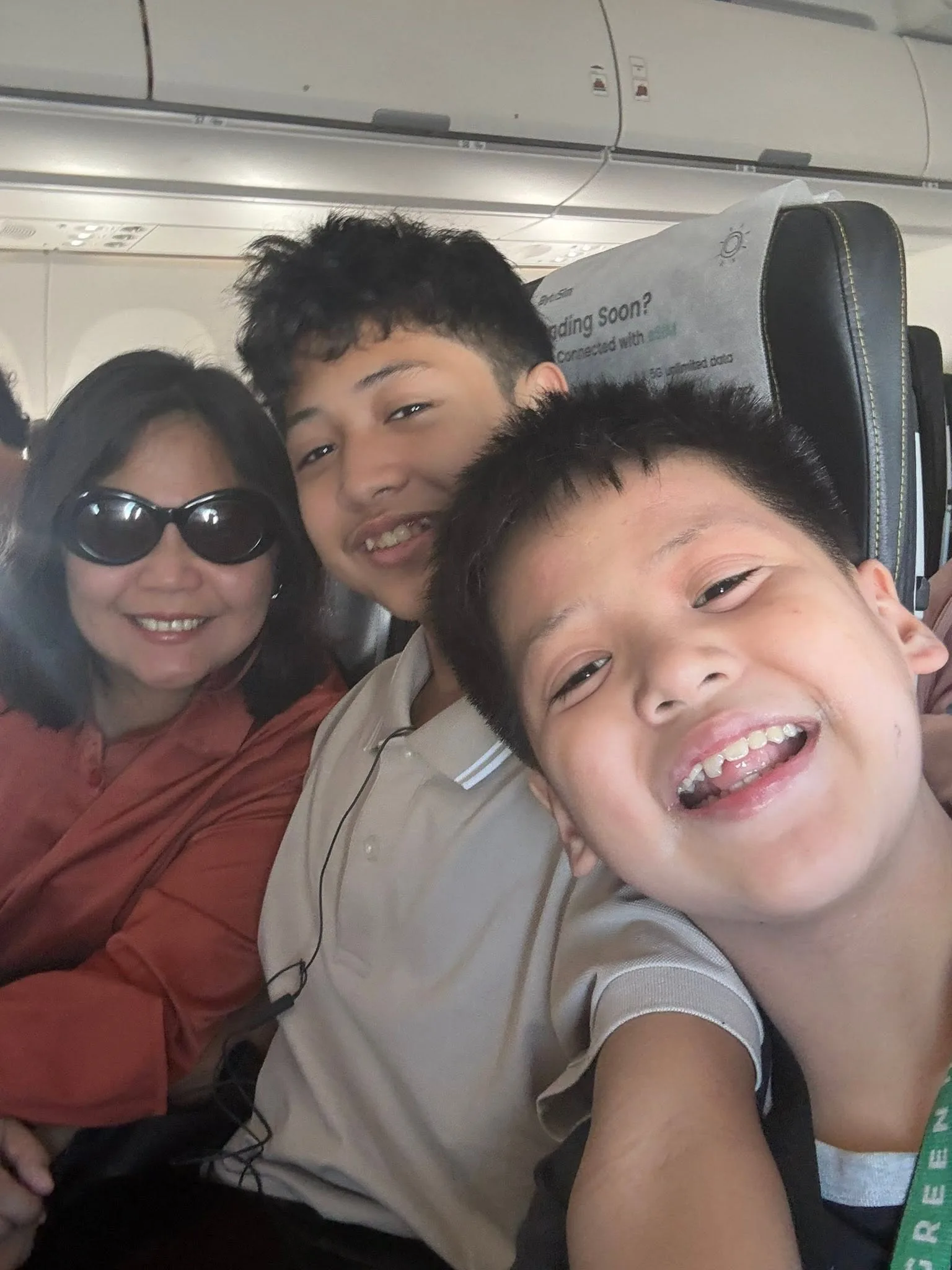 Lola and two grandsons laughing together on the flight to Singapore
