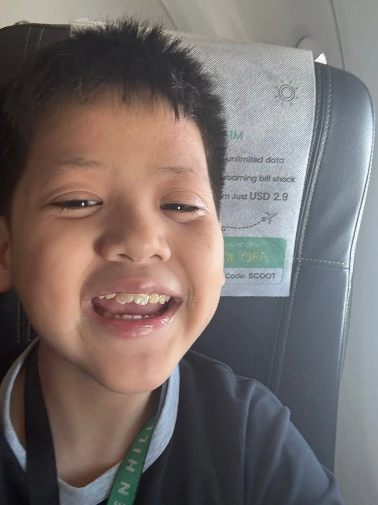 Young boy grinning in his plane seat, Singapore and Disney Adventure cruise bound