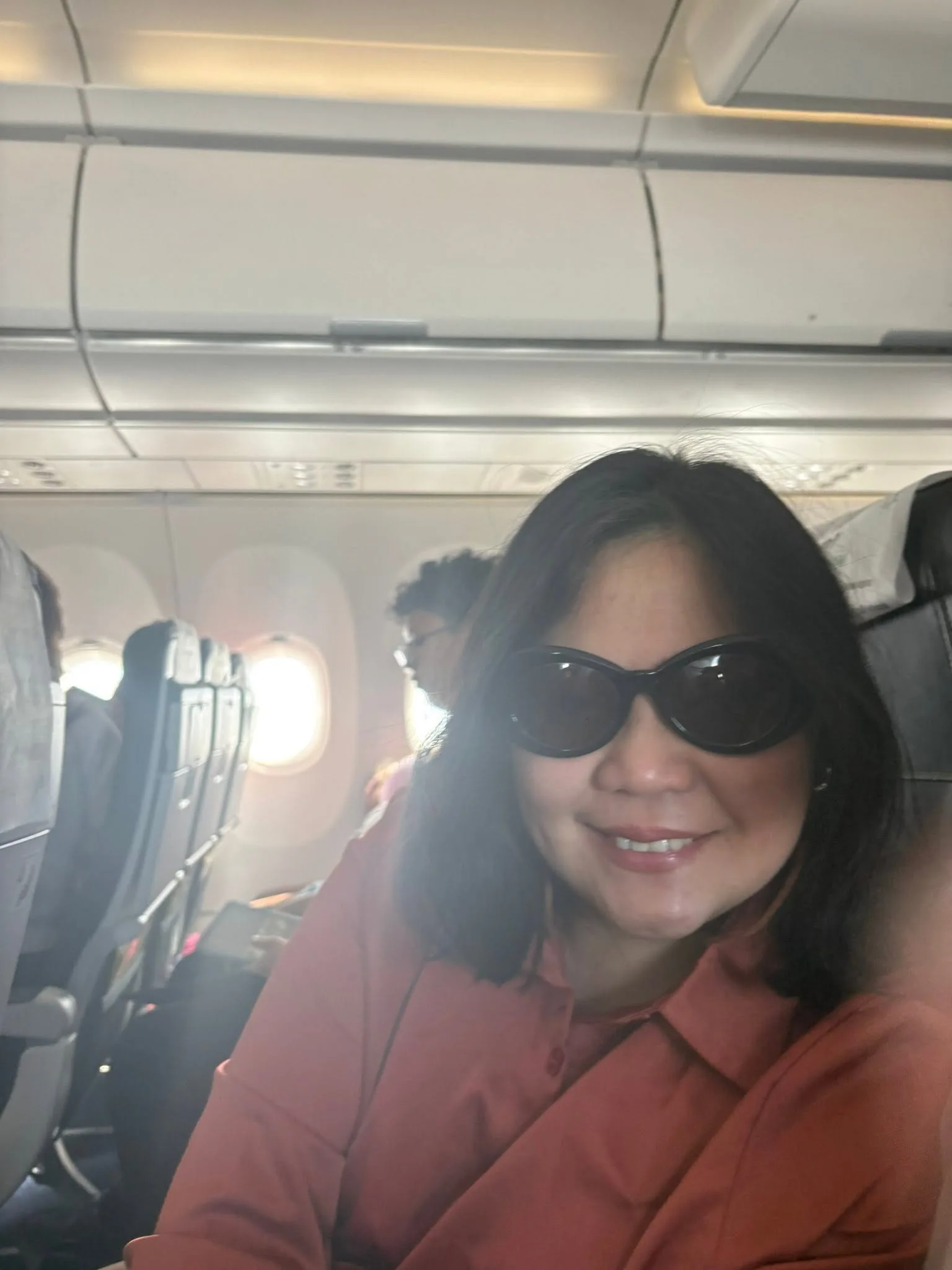 Lola in sunglasses smiling on the plane from Manila to Singapore