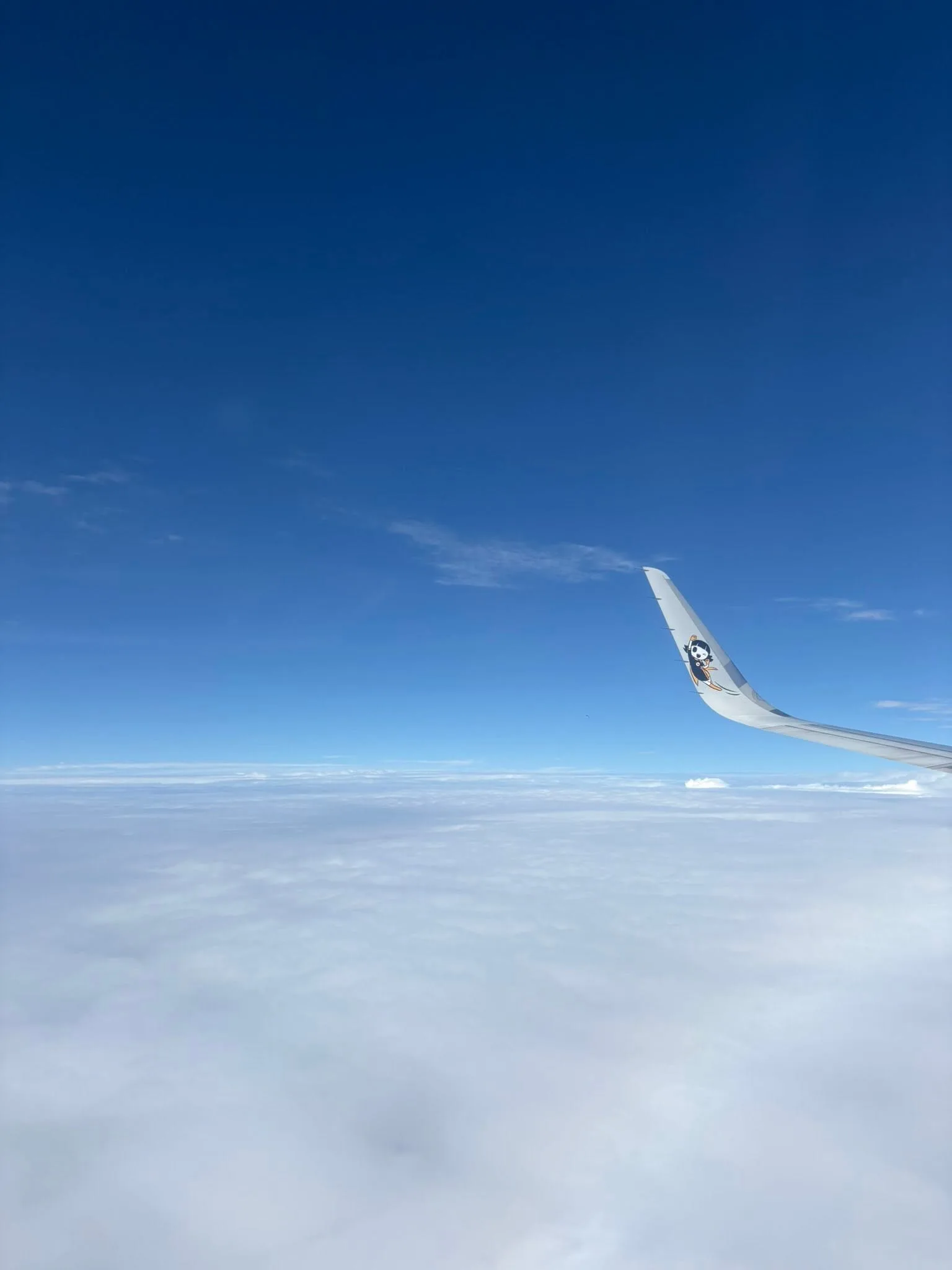 View of clouds and the plane wing on the flight from Manila to Singapore