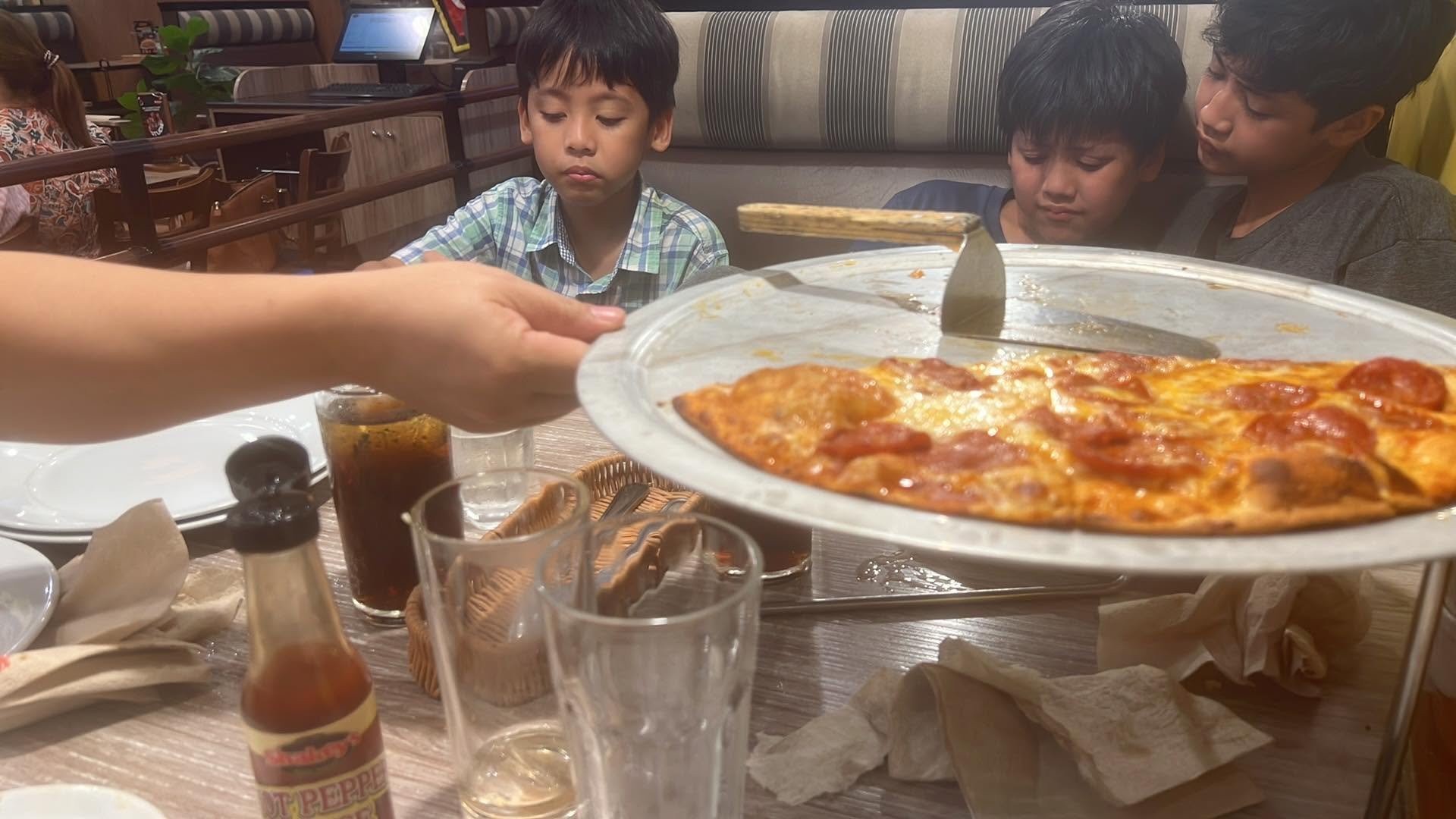 Pepperoni pizza being served to one of the boys at the Shakey's table
