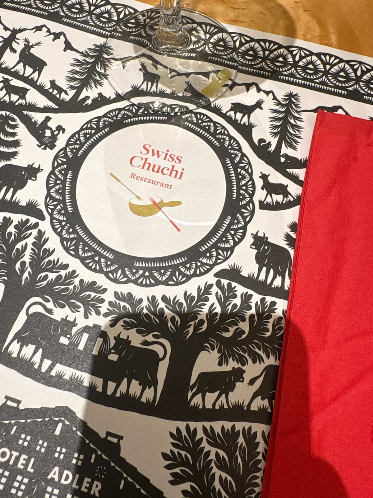 Swiss Chuchi paper placemat with a Swiss papercut scene of cows, trees and mountains