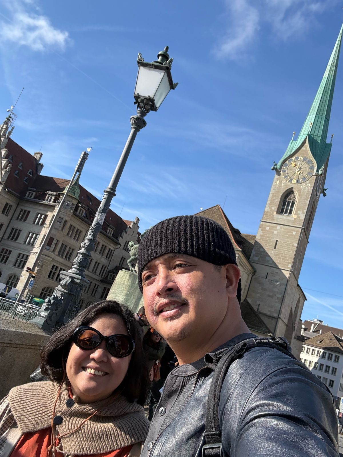 Dimple and Paolo by an old lamp post with the Fraumünster tower behind