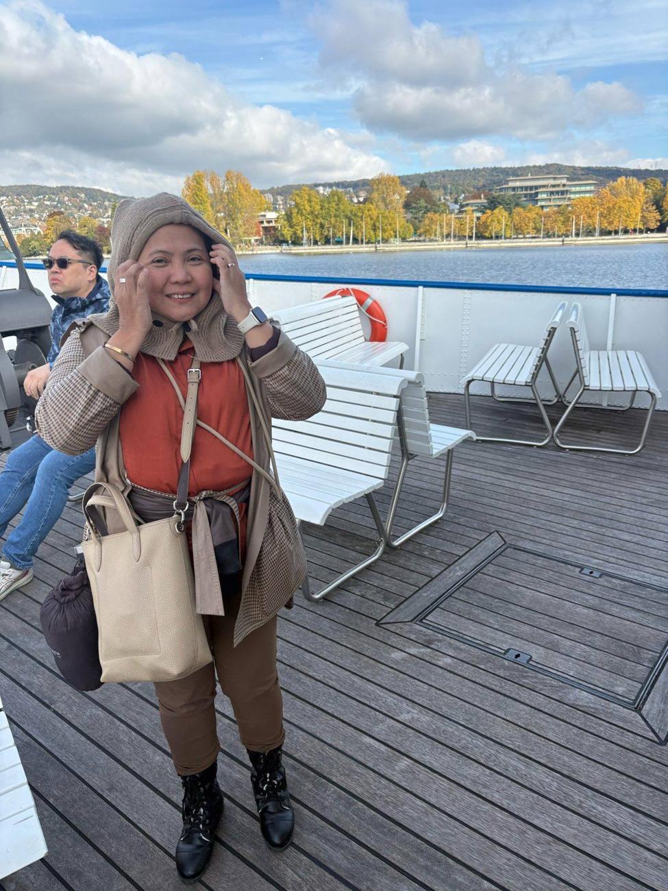 Hood up, hands on her ears, and still smiling in that lake wind.