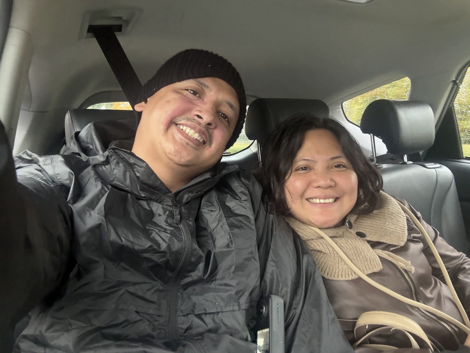 Paolo and Rosed smiling in a car on a rainy day in Zurich