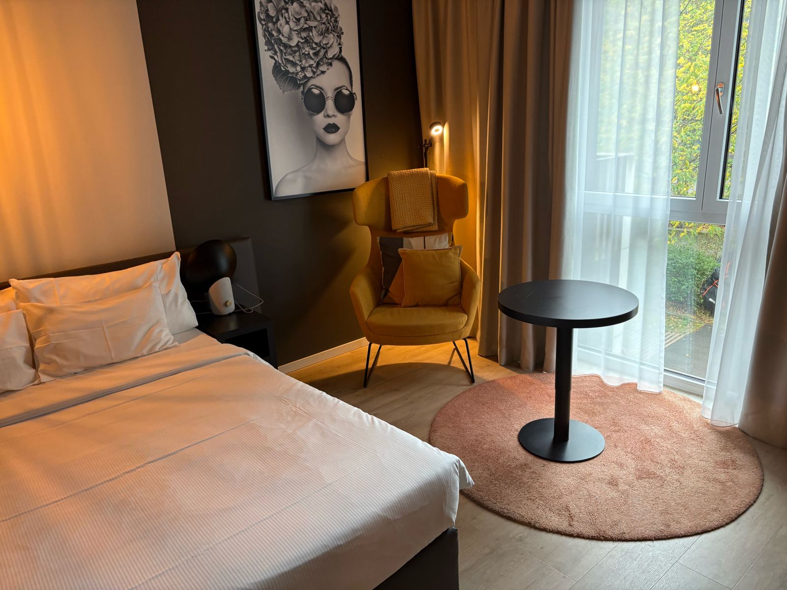 Radisson Hotel & Suites Zurich room with a yellow armchair, round table and big windows