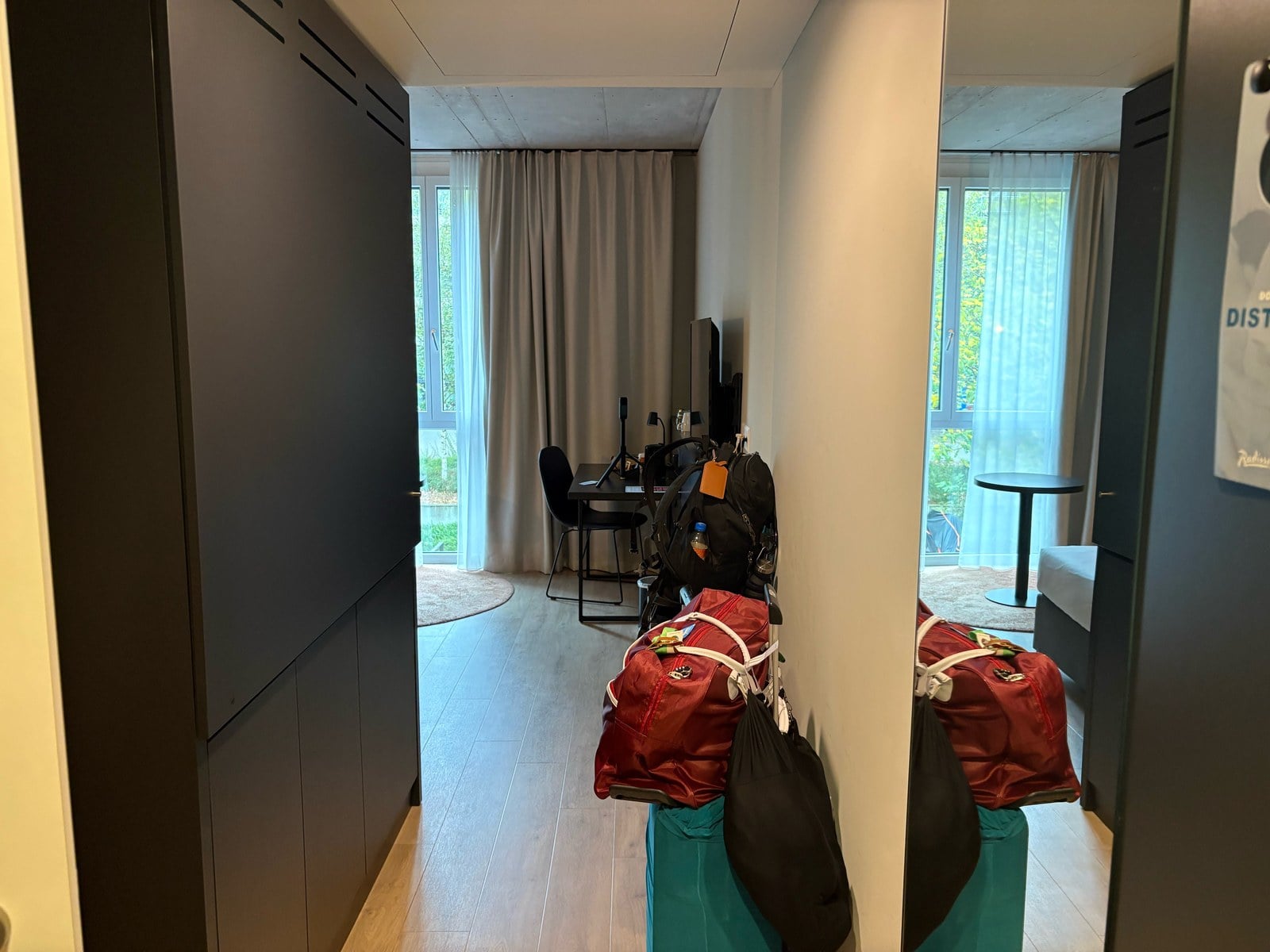 Radisson Hotel & Suites Zurich room entry hallway with dark cabinets, mirror and our bags
